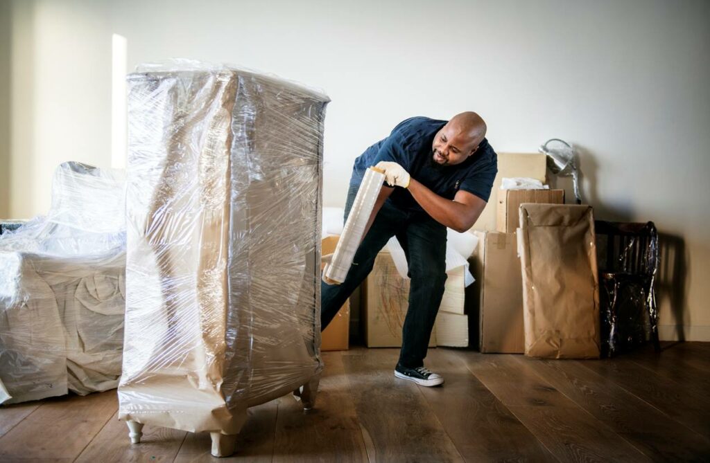 Man wrapping furniture for storage.