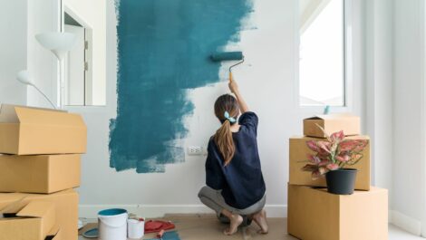 Woman painting inside of home with items packed for storage.